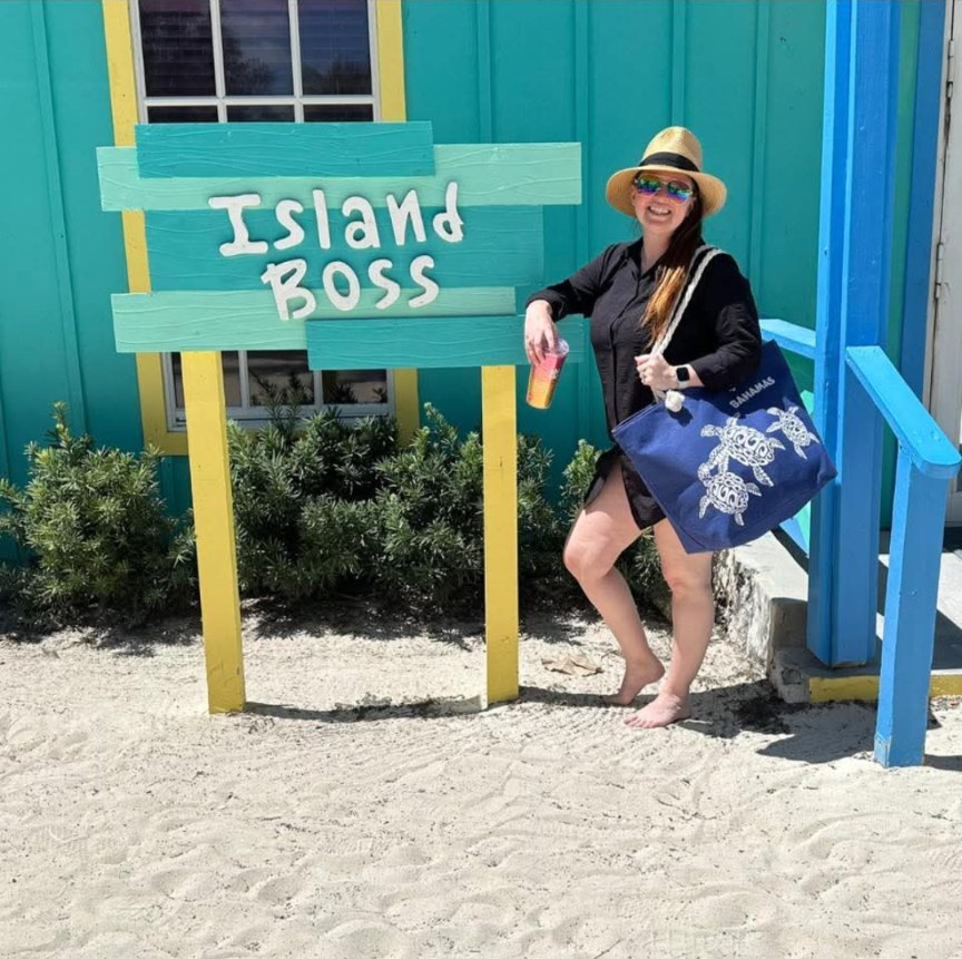 Tabitha at a beach sign that reads Island Boss